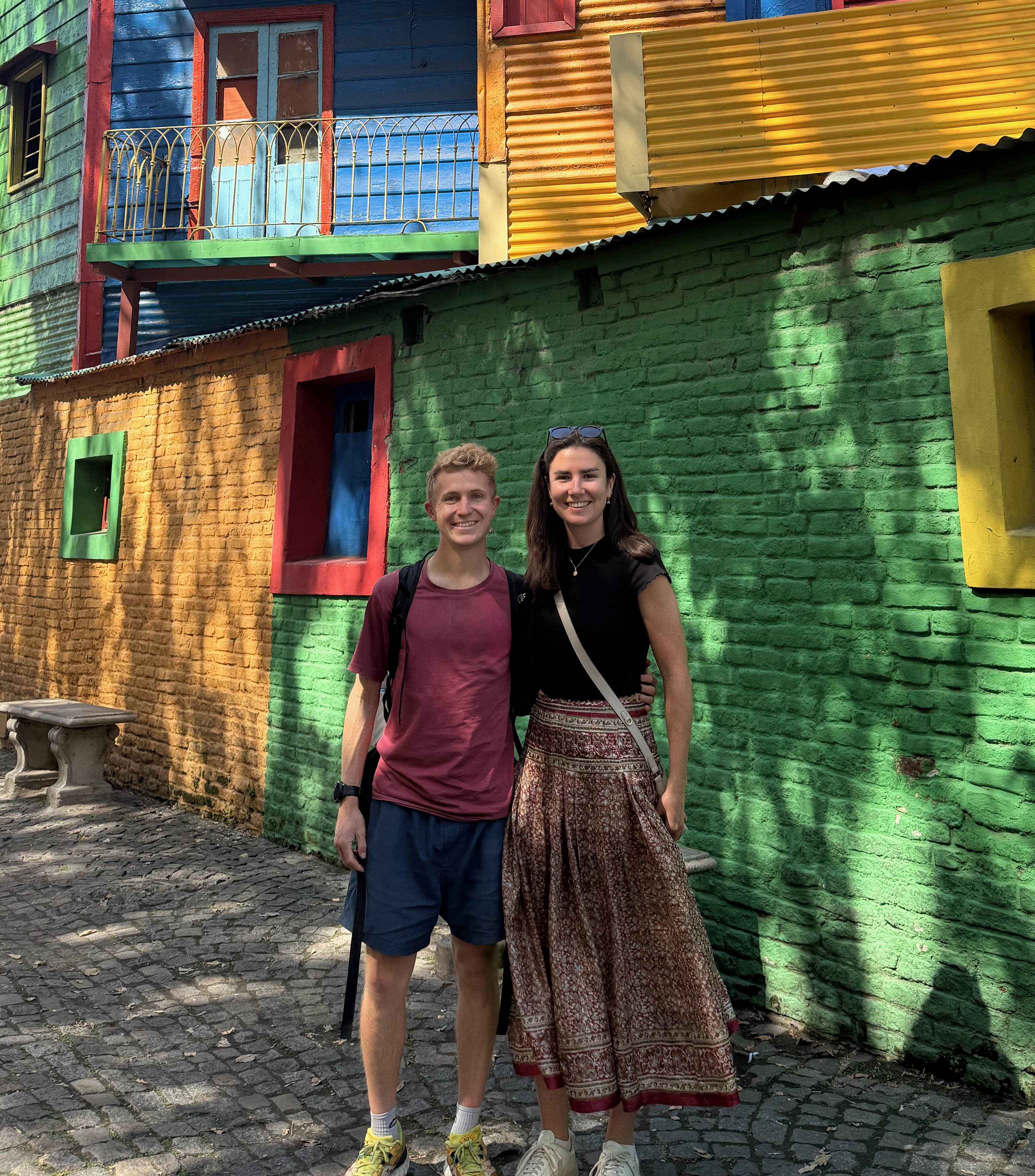 Victoria and Louis standing together beside colourful houses